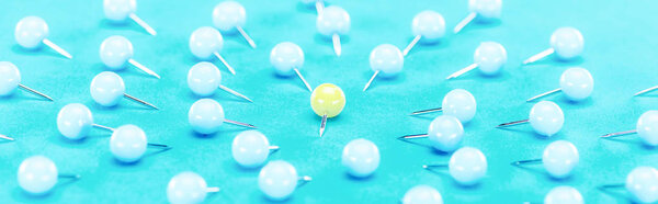 panoramic shot of yellow paper clip rounded by blue paper clips on blue background, violence concept