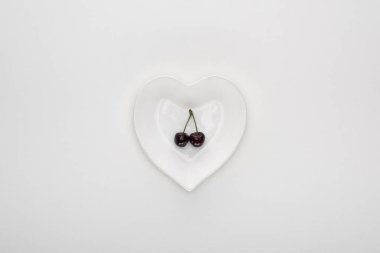 kalp şeklinde beyaz plaka üzerinde kırmızı ve taze kiraz üst görünümü 