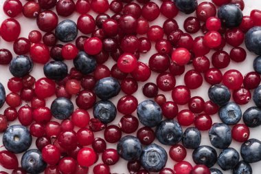 top view of red, fresh and ripe cranberries and whole blueberries  clipart