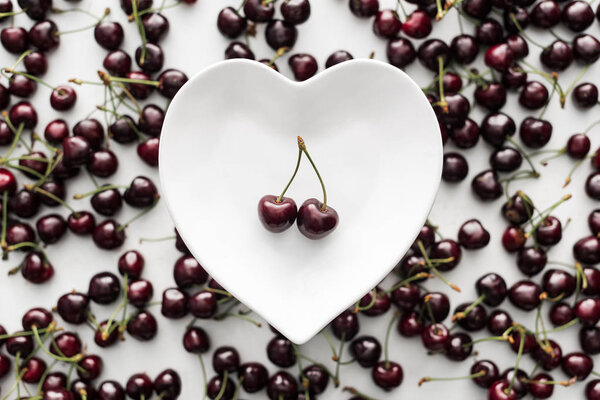 top view of ripe, fresh and sweet cherries on white plate 