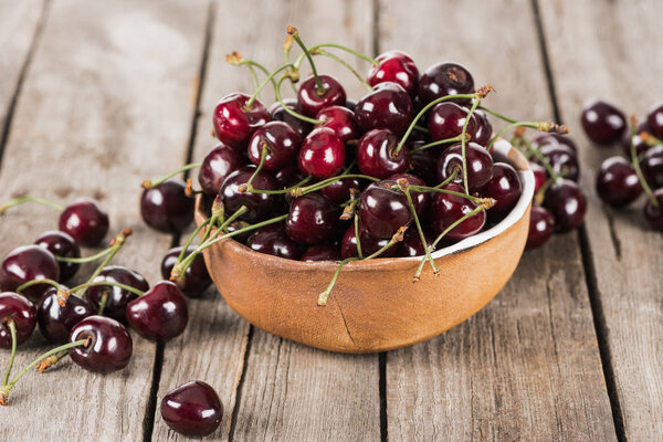 red, fresh, whole and ripe cherries on bowl on wooden surface 