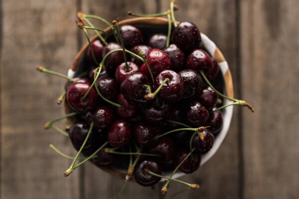 top view of red, fresh, whole and ripe cherries covered with droplets on bowl 