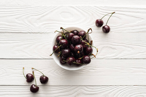 top view of fresh, sweet and ripe cherries on bowl on wooden background 