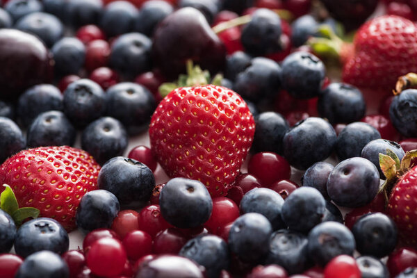 selective focus of red, fresh and ripe cranberries, strawberries, blueberries and cherries 