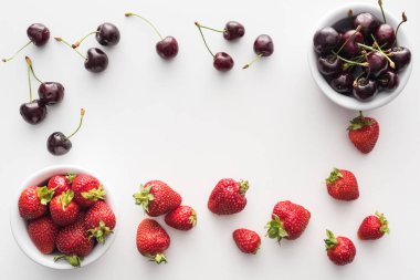 top view of sweet strawberries and fresh cherries on bowls  clipart