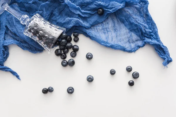 青い布の甘くて熟したブルーベリーとワイングラスのトップビュー — ストック写真