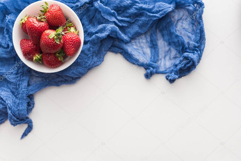 top view of sweet and whole strawberries on bowl with blue cloth 