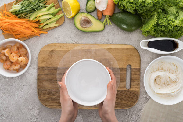 top view of woman holding white bowl with water 