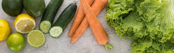 panoramic shot of lemons, limes, avocados, carrots and lettuce on table 