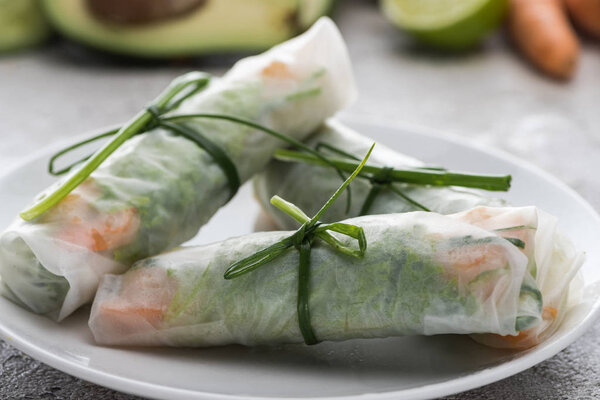 tasty and served spring rolls with onions on white plate 