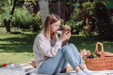 sevimli Galce Corgi köpek yavrusu ile bahçede beyaz battaniye üzerinde oturan ihale sarışın kız