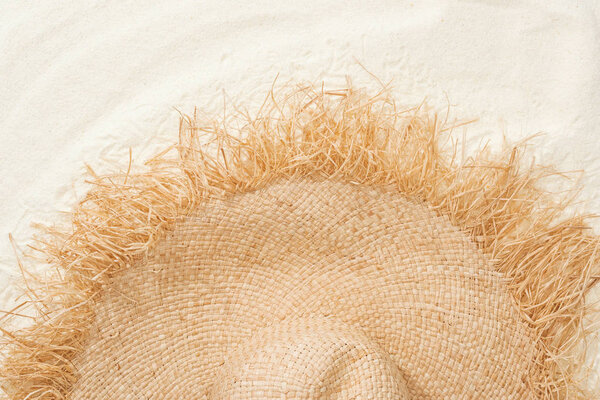 вид сверху на стильную соломенную шляпу на золотом песке
