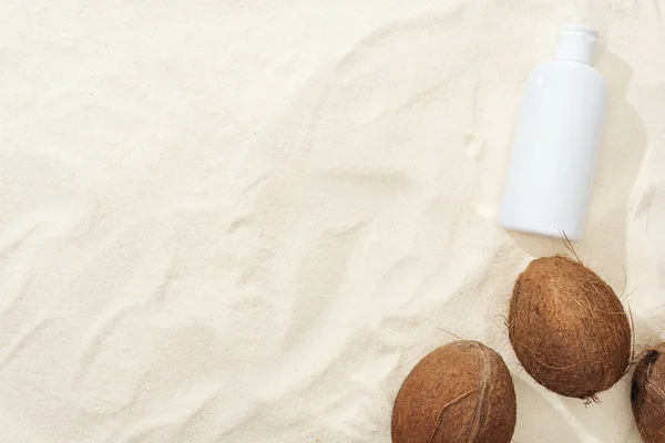 椰子和白色防晒霜的顶视图化妆水的沙上 — 图库照片