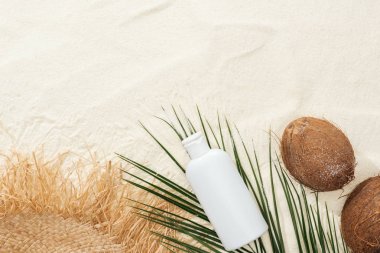 palmiye yaprağı, Hindistan cevizi ve kum üzerinde saman şapka ile güneş kremi losyonu üst görünümü