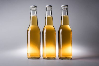 gri arka planda bira ile üç cam şişe