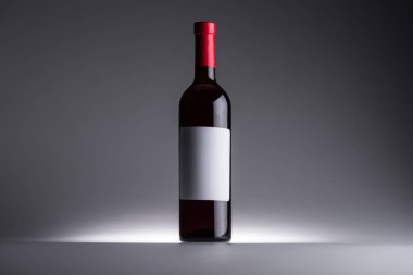 arka ışık ile koyu arka planda kırmızı şarap ve boş etiket şişe