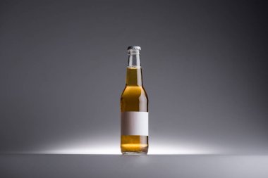 koyu gri arka planda bira ve boş etiket ile cam şişe