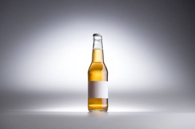gri arka plan üzerinde bira ve boş beyaz etiket ile cam şişe