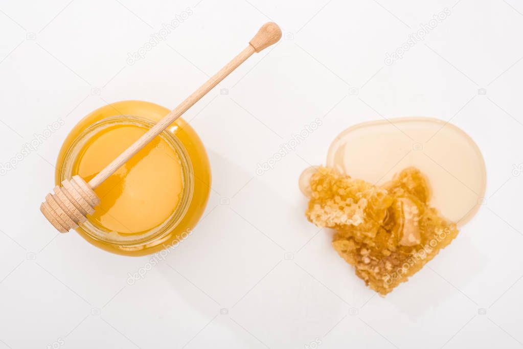 top view of jar with honey, honeycomb and wooden honey dipper on white background