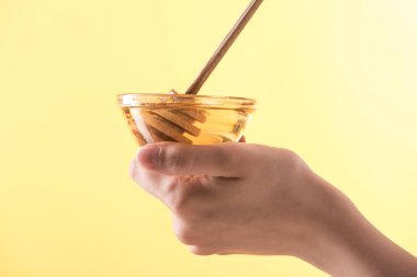 sarı üzerinde izole bal ve ahşap dipper ile kase tutan kadın kırpılmış görünümü