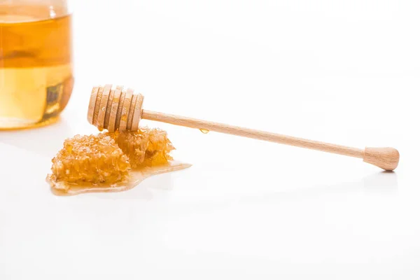 甘い蜂蜜と白に分離された瓶の近くに木製の蜂蜜ディッパーとハニカム — ストック写真