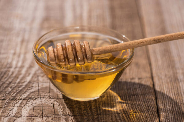 стеклянная чаша с вкусным медом и медовым окунем на деревянном столе при солнечном свете
