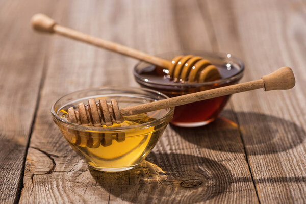 баночки с медом и медом на деревянном столе при солнечном свете
