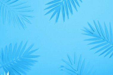 top view of paper leaves on blue minimalistic background with copy space clipart