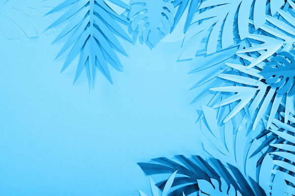 frame of paper leaves on blue minimalistic background with copy space