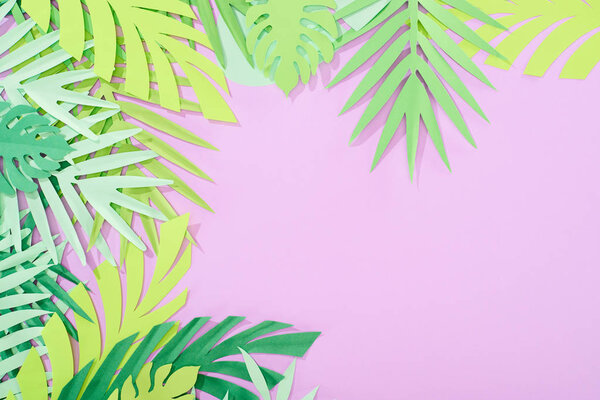 top view of green paper cut tropical leaves on violet background with copy space