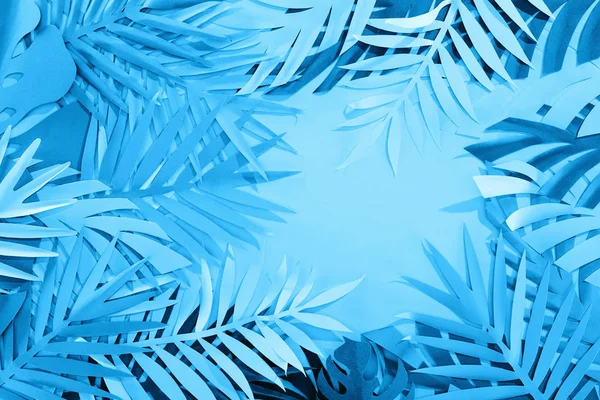 top view of paper leaves on blue minimalistic background with copy space