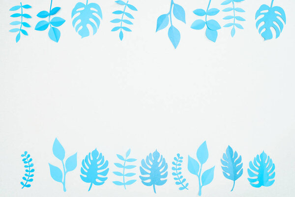 top view of blue paper cut tropical leaves isolated on white with copy space
