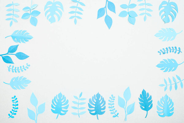 top view of blue paper cut tropical leaves isolated on white with copy space