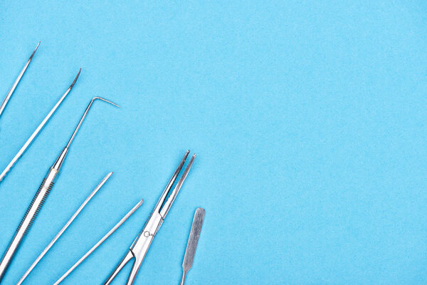 top view of set with stainless dental instruments isolated on blue 