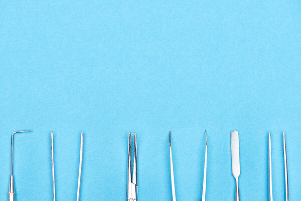 top view of set with metallic dental instruments isolated on blue 