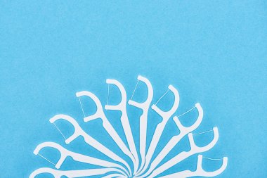 top view of white and plastic floss toothpicks isolated on blue  clipart