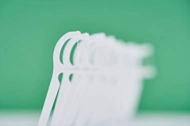 selective focus of white floss sticks isolated on green  clipart