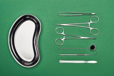 top view of metallic plate near set with dental tools and scissors isolated on green  clipart