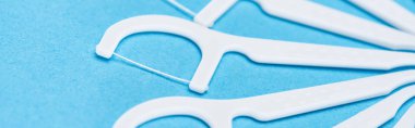 panoramic shot of white floss sticks isolated on blue  clipart