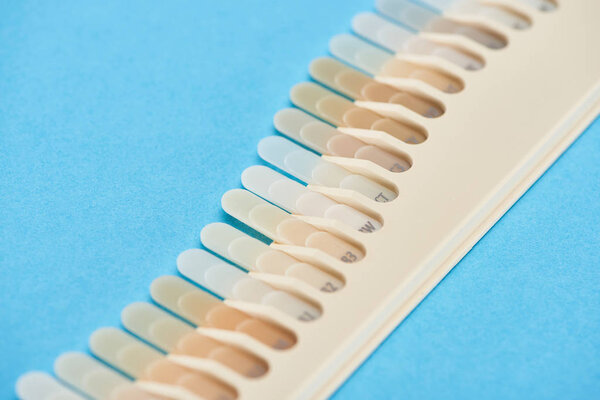 selective focus of teeth samples with different shades isolated on blue 