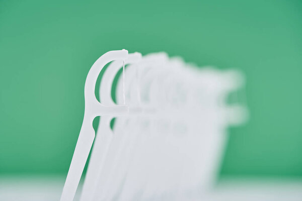 selective focus of white floss sticks isolated on green 