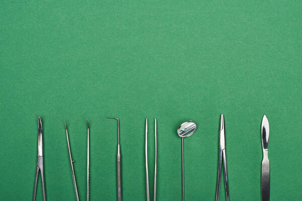 top view of set with stainless dental tools isolated on green 