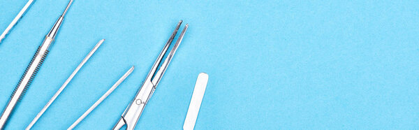 panoramic shot of set with stainless dental instruments isolated on blue 