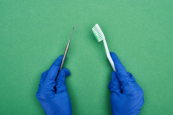 Vue Recadrée Dentiste Tenant Grattoir Dentaire Brosse Dents Sur Vert — Photo