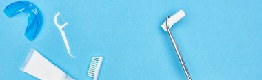 panoramic shot of tweezers with cotton pad near toothpaste and toothbrush on blue  clipart