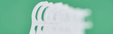 panoramic shot of white floss toothpicks isolated on green  clipart
