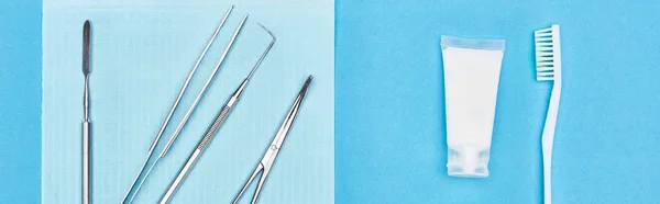 在牙膏和牙刷附近用牙科工具在蓝色上隔离的全景照片 — 图库照片