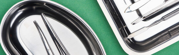 panoramic shot of set with dental tools in metallic plates isolated on green 