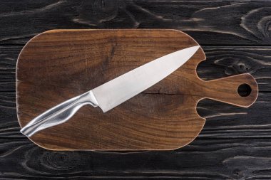 top view of wooden cutting board with knife on table  clipart
