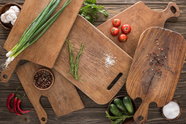 top view of cutting boards, cherry tomatoes, salt, garlics, cucumbers, chili peppers and spices 